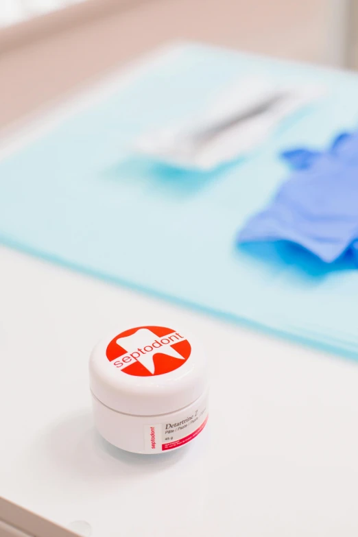 a toothbrush sitting on top of a table next to a container of toothpaste, a picture, silicone patch design, red cross, product, surgeon