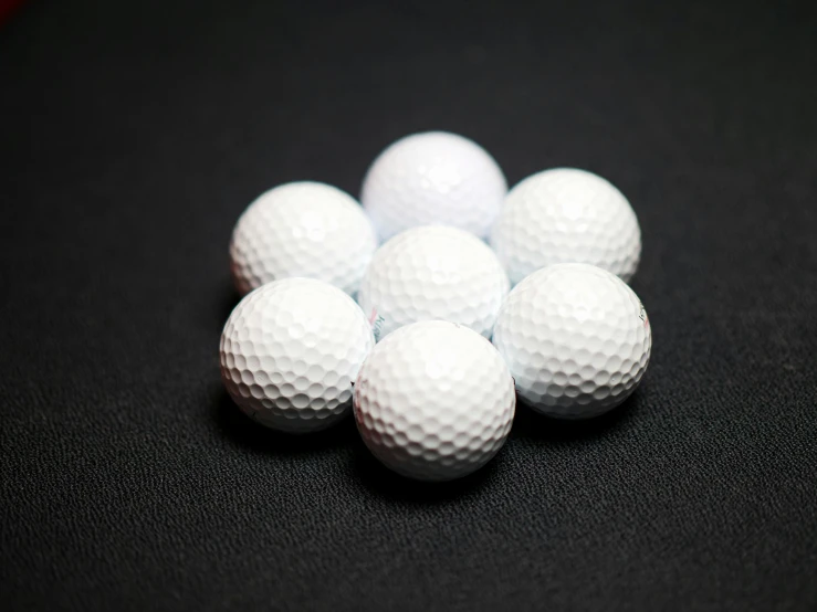 a pile of golf balls on a black surface, by Joe Bowler, unsplash, six sided, decoration, on white, high quality product image”