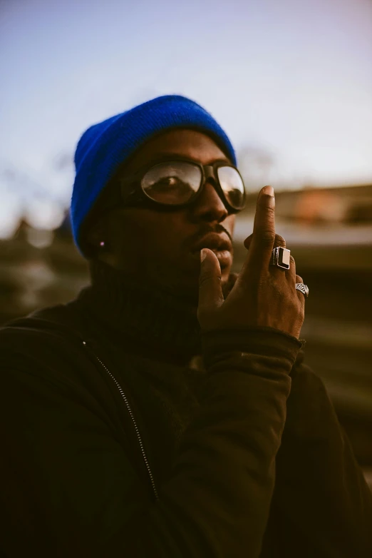 a man in a blue beanie smoking a cigarette, an album cover, inspired by Zhu Da, trending on pexels, mkbhd, superhero, high quality photo, vanta blac