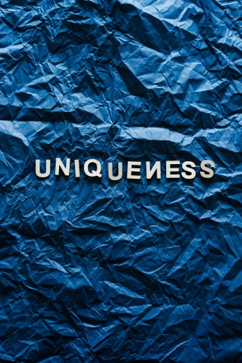 a blue crumpled piece of paper with the word uniqueness written on it, an album cover, unsplash, heavily stylized, elegantly dressed, new album cover, carousel