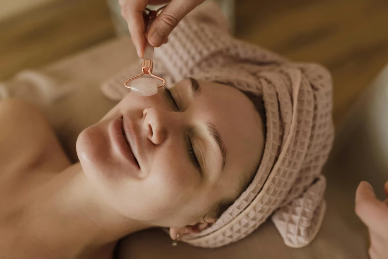 a woman getting a facial treatment at a spa, by Emma Andijewska, trending on pexels, art nouveau, rose quartz, thumbnail, brown, vibrating