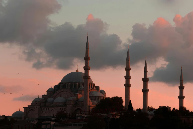 a large building with many spires in front of a cloudy sky, an album cover, by Ismail Acar, pexels contest winner, hurufiyya, pink white turquoise, late summer evening, ottoman empire, skyline showing