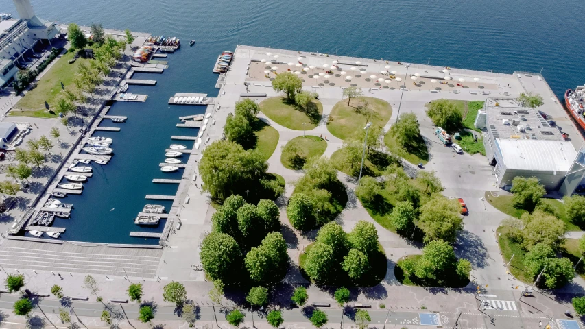 a marina filled with lots of boats next to a large body of water, by karlkka, land art, green square, ignant, linden trees, airborne view