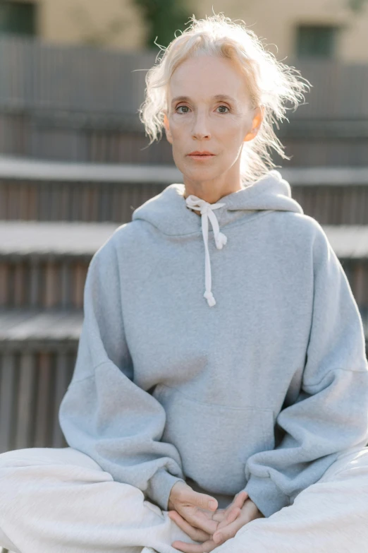 a woman sitting in the middle of some stairs, a portrait, by Grace Polit, trending on pexels, minimalism, grey hoodie, 5 5 yo, may gibbs, voluminous sleeves