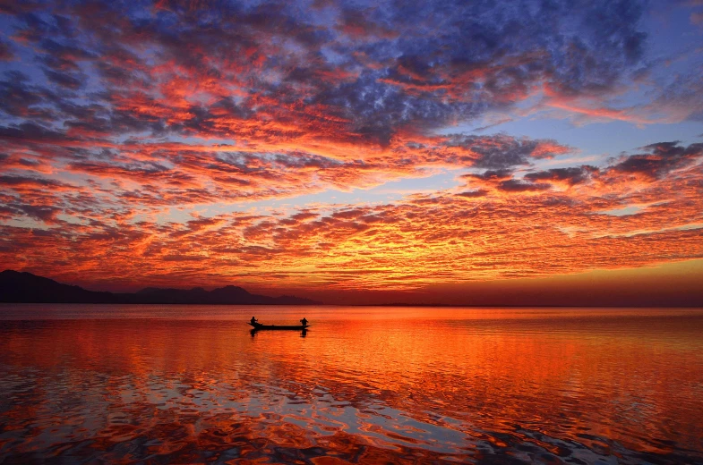 a boat floating on top of a large body of water, by Jan Tengnagel, pexels contest winner, romanticism, orange and red sky, infinite, high detailed photo, awarded winning photo