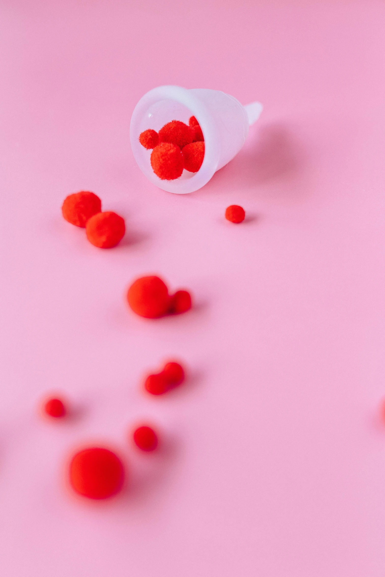 red pom poms scattered on a pink surface, a picture, inspired by Kusama, pexels, plasticien, cups and balls, molecular gastronomy, cone, contracept