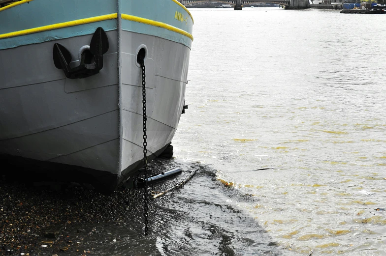 a large boat sitting on top of a body of water, on a wet london street, oil slick in the water, upclose, photo from the side