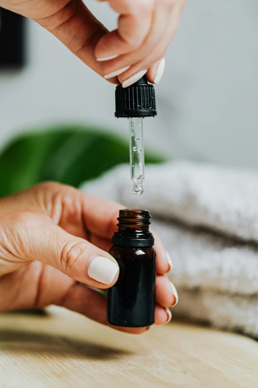 a close up of a person holding a bottle of essential oil, by Nicolette Macnamara, thumbnail, drops, item, spa
