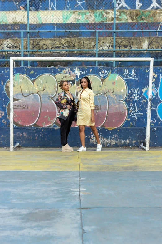 a couple of women standing next to each other on a tennis court, an album cover, pexels contest winner, graffiti, location ( favela _ wall ), football, 15081959 21121991 01012000 4k