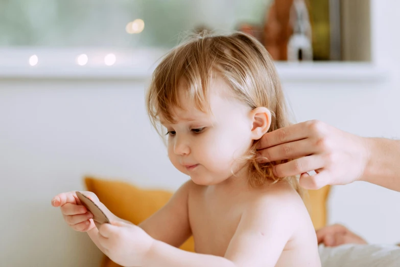 a woman combing a child's hair while sitting on a couch, trending on pexels, pale pointed ears, acupuncture treatment, phone photo, portrait of small
