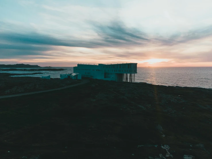 a building sitting on top of a hill next to the ocean, by Jesper Knudsen, pexels contest winner, olafur eliasson, end of day, research station, boards of canada