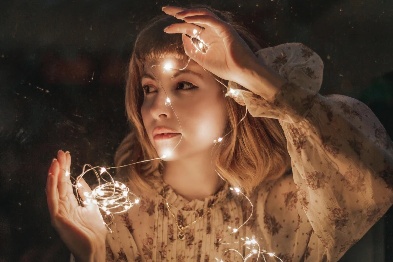 a woman holding a sparkler in her hands, an album cover, inspired by Elsa Bleda, trending on pexels, magical realism, side portrait of imogen poots, fairy lights, lumen reflections, amy sol in the style of