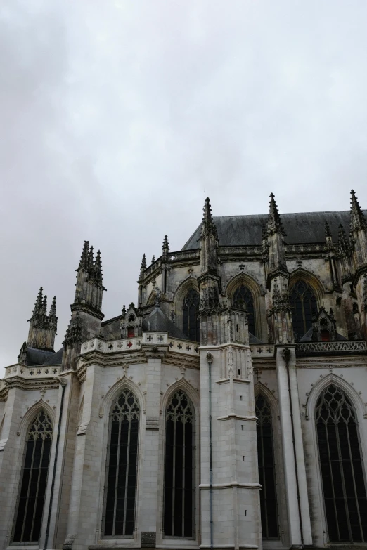a very tall building with a lot of windows, a statue, by Jacob Koninck, baroque, dark gothic cathedral, grey sky, flying buttresses, northern france