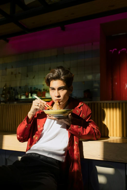 a man sitting at a table with a plate of food, an album cover, inspired by Reuben Tam, trending on unsplash, non binary model, 8 0 s asian neon movie still, model posing, swedish