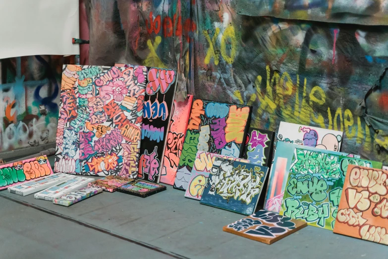 a group of paintings sitting on top of a table, graffiti, stickers, multi - coloured, acid graphix, professional art