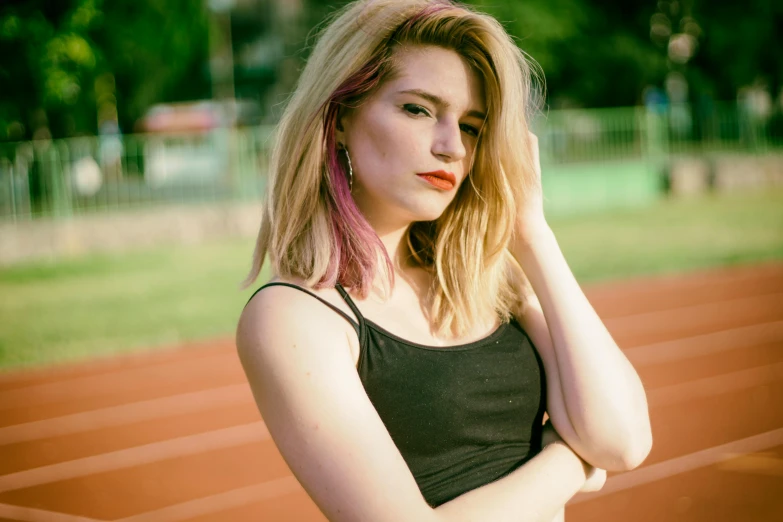 a woman with pink hair standing on a track, an album cover, inspired by Elsa Bleda, unsplash, realism, brown-blond-hair pretty face, she is wearing a black tank top, on a soccer field, lipstick