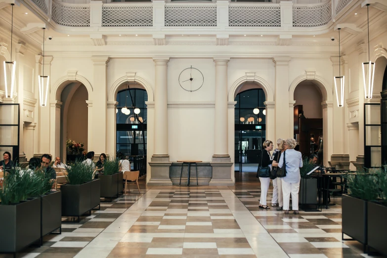 a couple of people that are standing in a building, high ceilings, town hall, lounge, marble floors