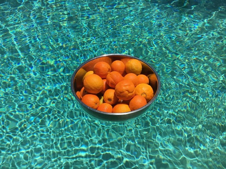 a bowl filled with oranges sitting on top of a swimming pool, 🦩🪐🐞👩🏻🦳, thumbnail, food, in the water
