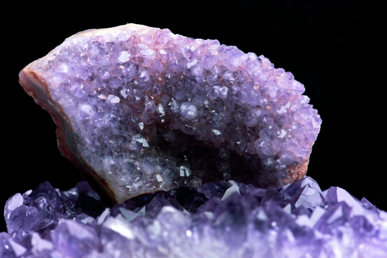 a piece of amethorate sitting on top of a pile of crystals, trending on pexels, ((purple)), close up shots, universal, round-cropped