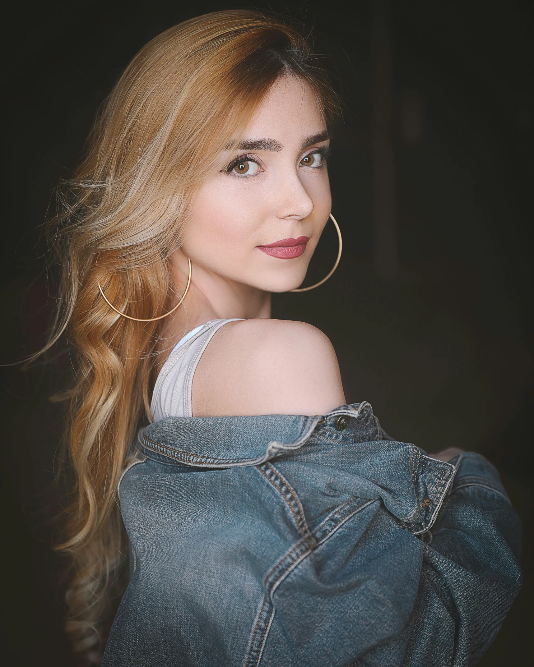 a woman with long hair wearing a denim jacket, inspired by Elsa Bleda, trending on pexels, better known as amouranth, brown-blond-hair pretty face, color corrected, glam photo