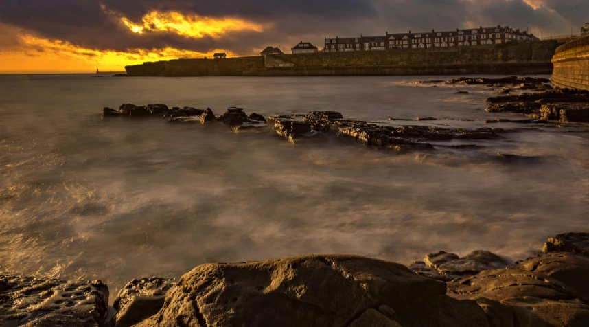 a large body of water next to a rocky shore, by Peter Churcher, pexels contest winner, happening, sunset beach, the harbour at stromness orkney, slide show, brown