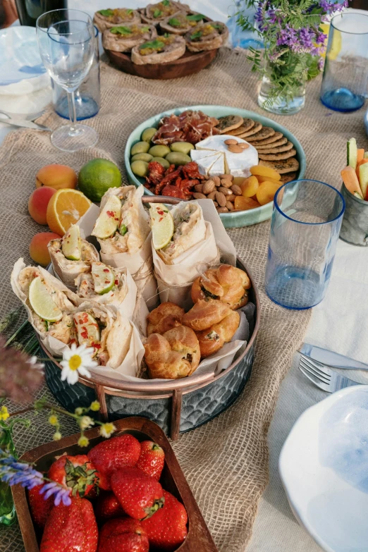 a table that has a lot of food on it, sunlit sky, breads, bowl filled with food, entertaining