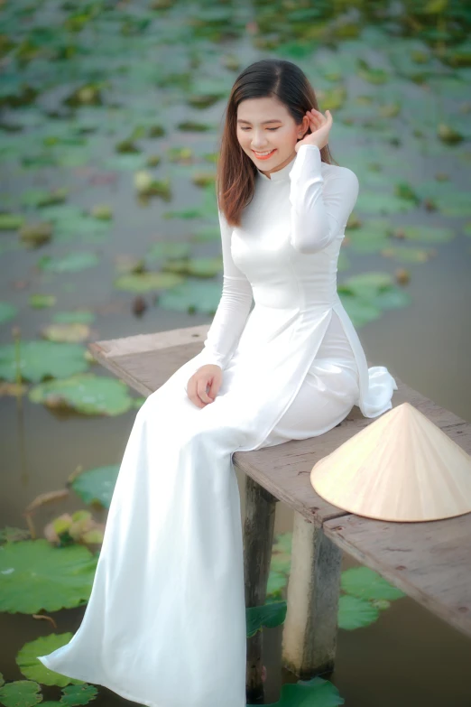 a woman in a white dress sitting on a wooden bench, inspired by Tan Ting-pho, pexels contest winner, happening, ao dai, standing on a lotus, white clothing, square