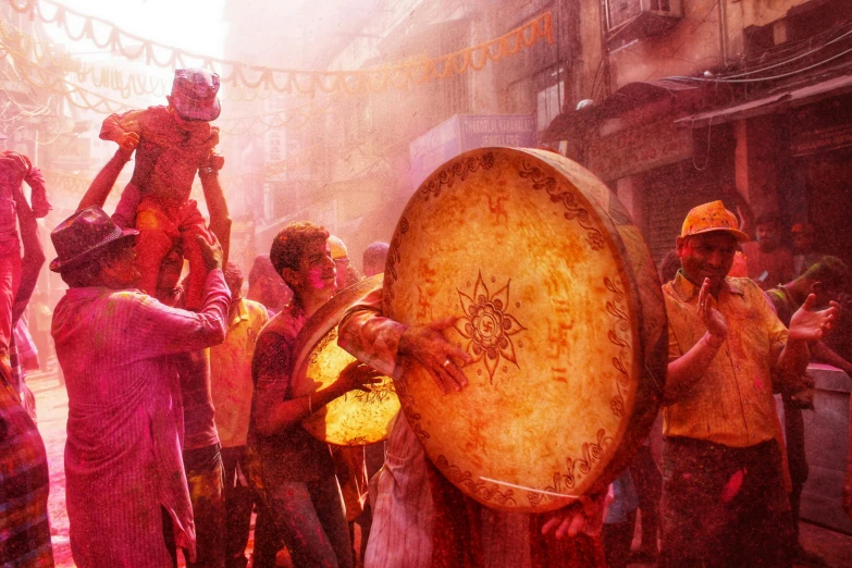 a group of people standing around a drum, a colorized photo, pexels contest winner, process art, nepal, magical sparkling colored dust, craig mullins style, red and yellow scheme