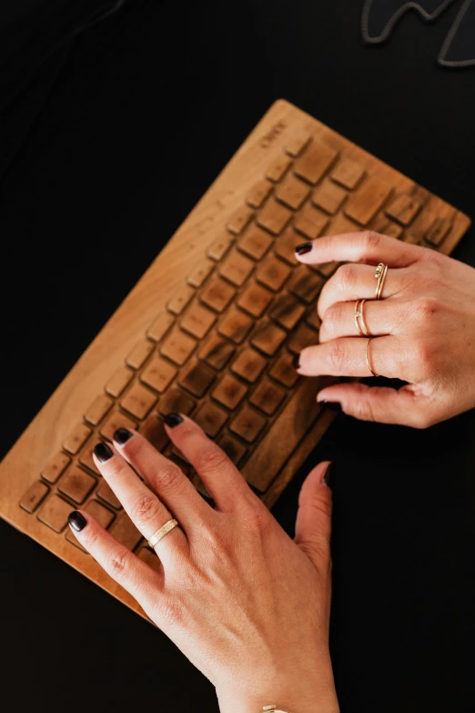 a close up of a person typing on a keyboard, inspired by L. A. Ring, wooden jewerly, gold rings, handcrafted, wood