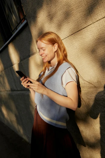 a woman standing on a sidewalk looking at her cell phone, flowing ginger hair, with dappled light, mobile app, curated collections