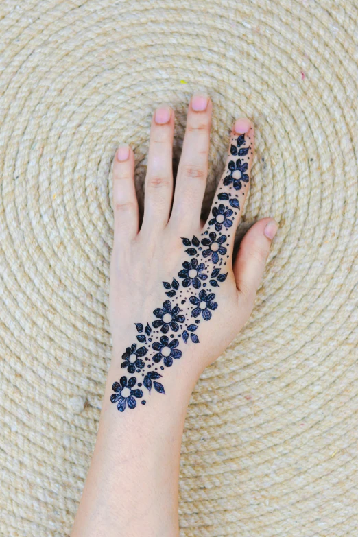 a woman's hand with a tattoo on it, trending on pexels, arabesque, made of flowers and berries, blue-black, 8 x, black