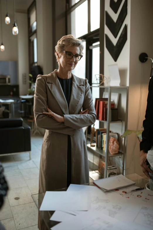 a woman standing next to a man in a room, wearing a suit and glasses, [ cinematic, older woman, cait miers