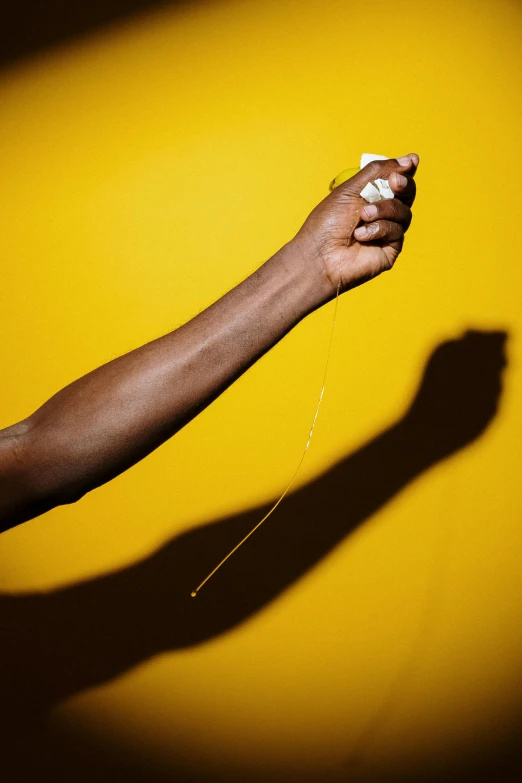 a person holding a yellow object in their hand, by Andrew Domachowski, pulling strings, dark skin, getty images, violence