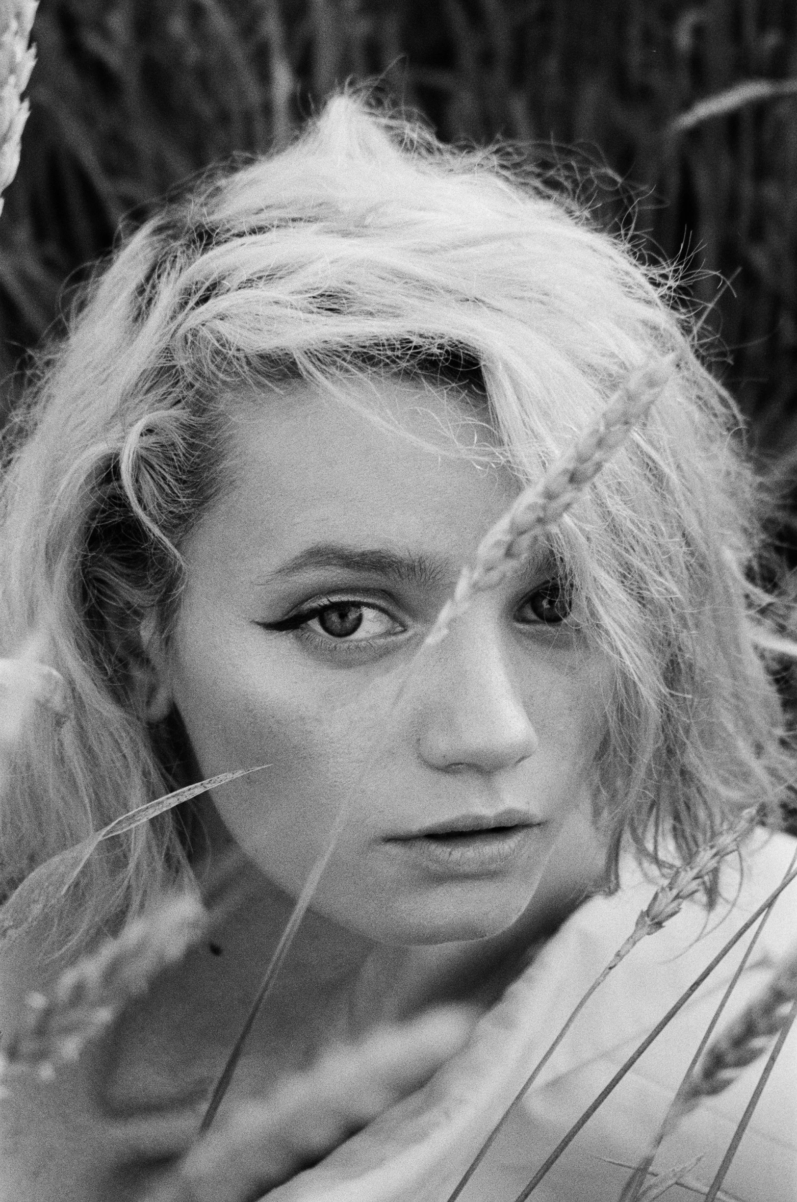 a black and white photo of a woman in a field, inspired by Cindy Sherman, reddit, dakota fanning, square, high quality photo, closeup portrait