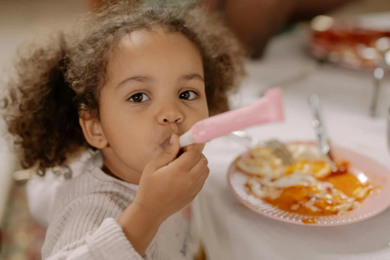 a little girl sitting at a table with a plate of food, with a gullet at the end, holding hot sauce, long pointy pink nose, 5k