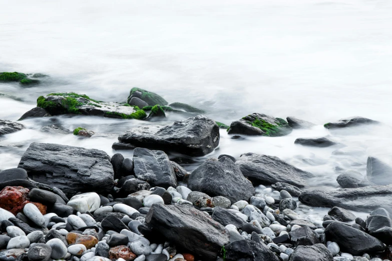 a bunch of rocks sitting on top of a beach, an album cover, unsplash, muted green, long exposure 8 k, ((rocks)), grey