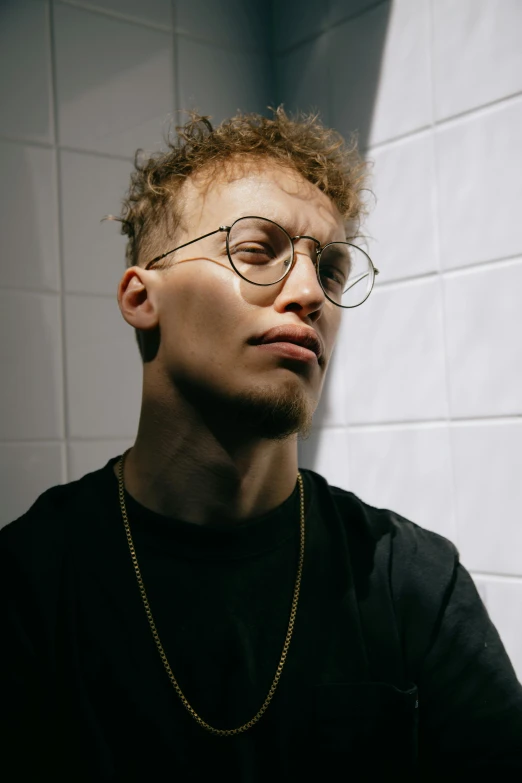 a man with glasses and a chain around his neck, an album cover, inspired by Sam Charles, trending on pexels, antipodeans, non binary model, looking to his left, light skin, curly haired