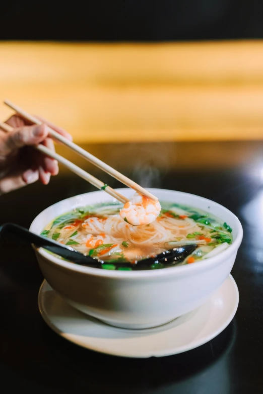 a person holding chopsticks over a bowl of soup, daily specials, shrimp, iconic scene, square