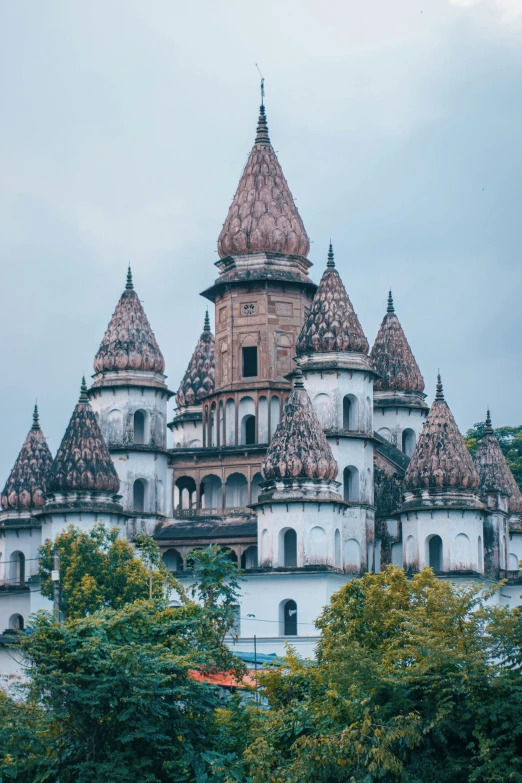 a large white castle sitting on top of a lush green hillside, inspired by Károly Lotz, unsplash contest winner, art nouveau, khajuraho, kremlin, dark gloomy church, majestic spires