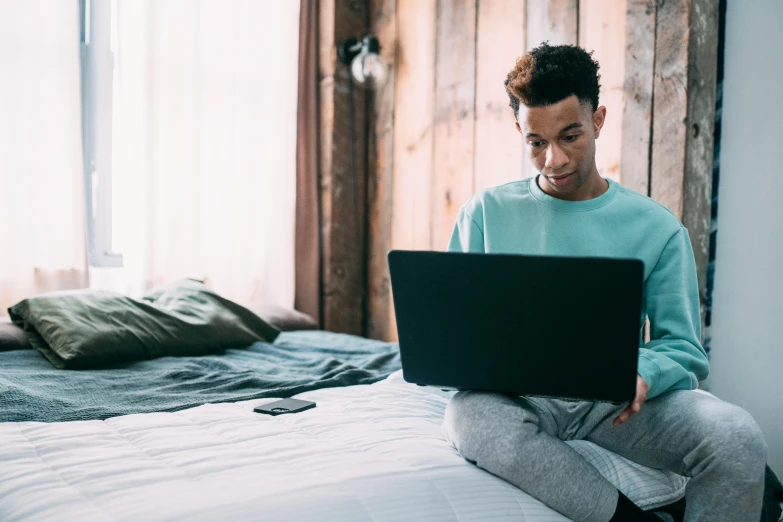 a man sitting on a bed using a laptop, by Carey Morris, trending on pexels, renaissance, with teal clothes, ashteroth, thin young male, thumbnail