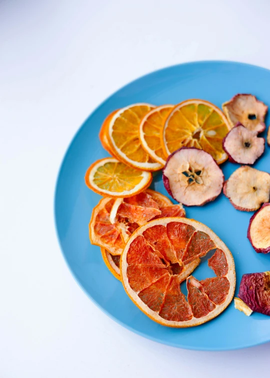 a blue plate topped with sliced oranges and apples, dry, fruggles, 6 pack, multicoloured