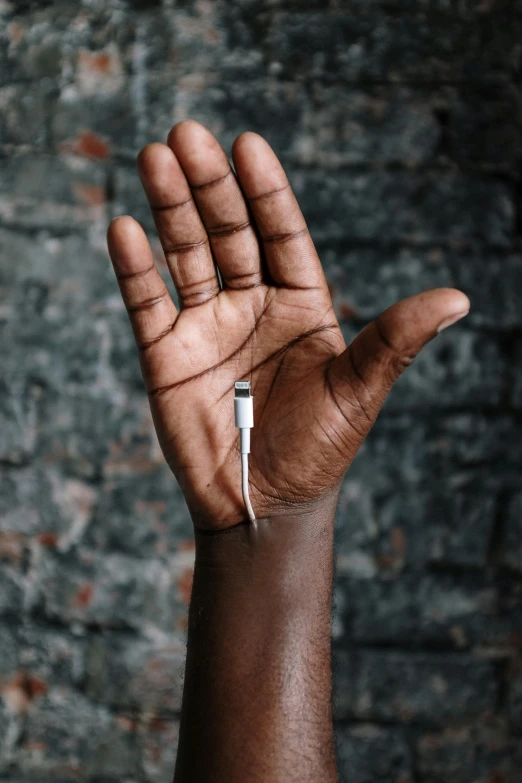 a close up of a person's hand holding a toothbrush, by Alison Geissler, trending on pexels, afrofuturism, cable wires as hair, holding holy symbol, earbuds, ignant