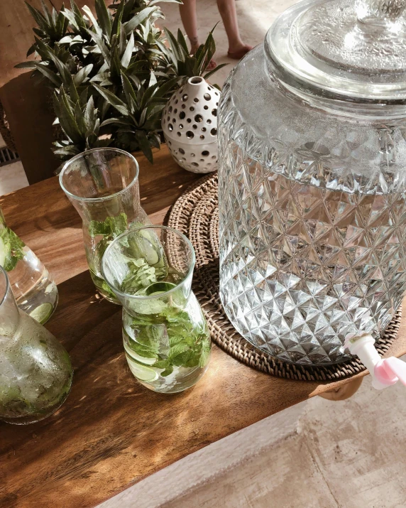 a glass jar sitting on top of a wooden table, water fountain, on a table