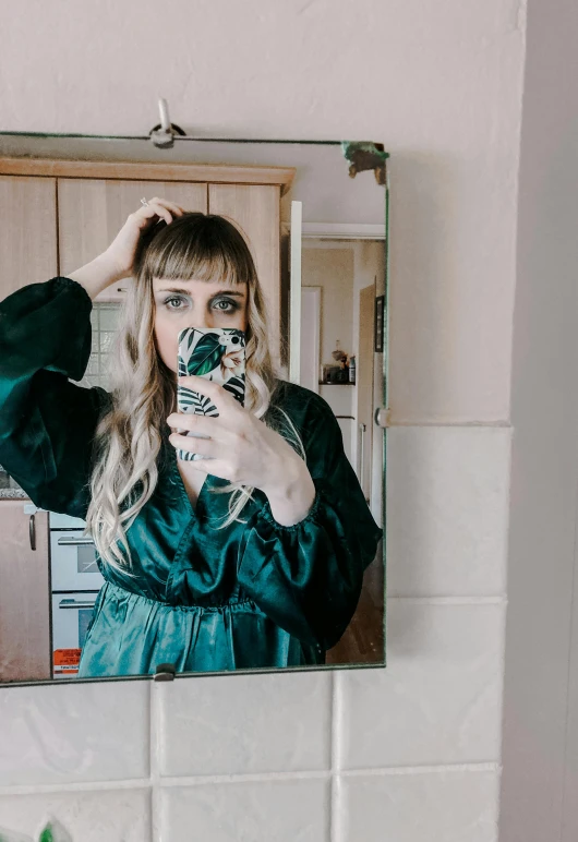 a woman taking a picture of herself in a mirror, an album cover, inspired by Elsa Bleda, trending on pexels, green robe, bangs and wavy hair, irish youtuber, leaked photo