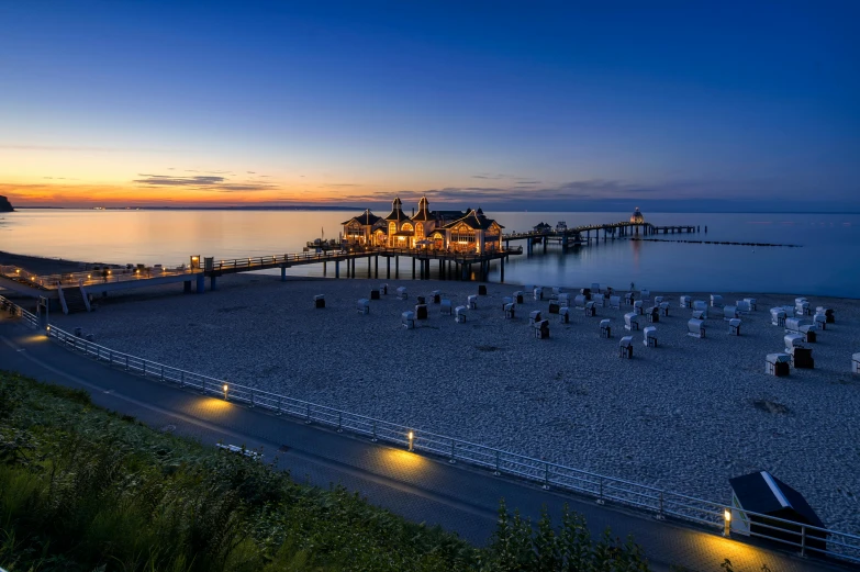 a pier that is next to a body of water, by Ulrich Leman, pexels contest winner, art nouveau, on the beach during sunset, blue hour lighting, 2 5 6 x 2 5 6 pixels, group photo