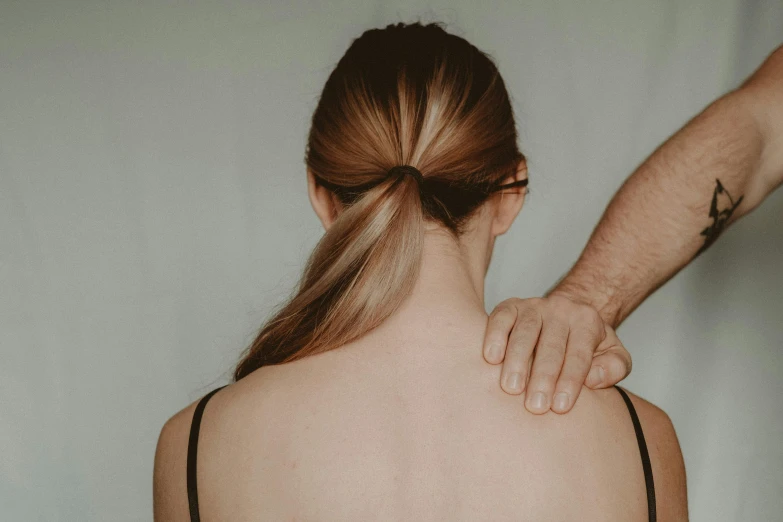 a woman standing next to a man with a tattoo on her back, trending on pexels, acupuncture treatment, brown hair in a ponytail, neck up, straya