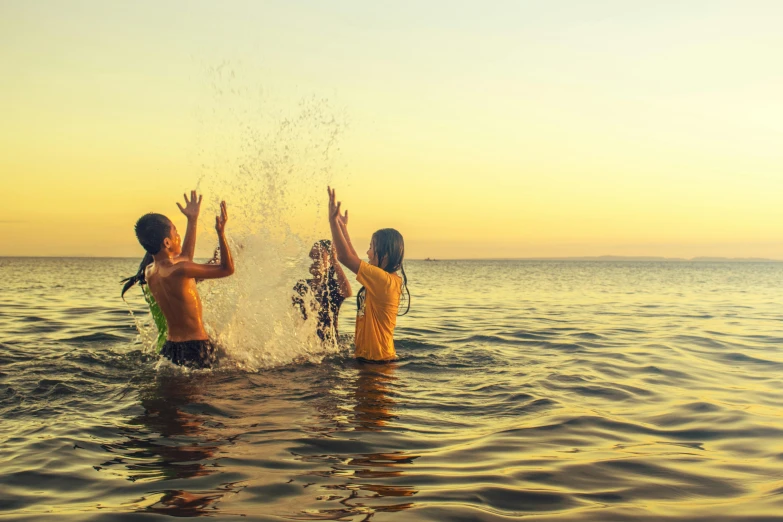 a couple of people that are in the water, by Carey Morris, pexels contest winner, kids playing, waving, summer evening, cardboard