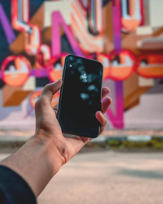 a person taking a picture of a graffiti wall, by Robbie Trevino, pexels contest winner, hyperrealism, one holds apple in hand, vantablack wall, ios app icon, blurred