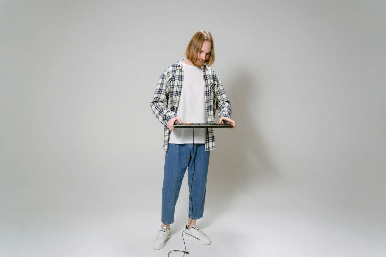 a man holding a laptop computer in one hand and a tennis racket in the other, an album cover, by Matthias Stom, unsplash, computer art, baggy jeans, wearing a flannel shirt, full body 1 / 6 nihei tsutomu, studio portrait photo