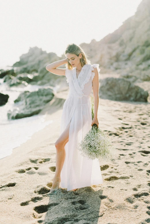 a woman standing on top of a sandy beach, exquisite floral details, soft white glow, wearing a toga and sandals, award - winning